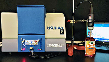 Raman spectra of DayQuil™ and NyQuil™ collected with an immersion probe fiber-coupled to the MacroRAM™ Raman spectrometer, and a picture of the immersion probe setup.
